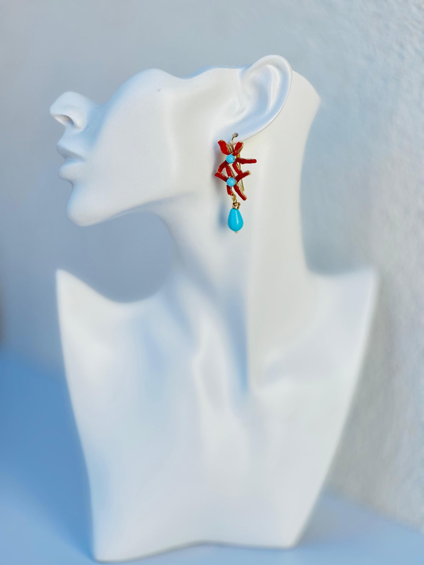 Orecchini RAWNA pendenti con base a stella marina in zamak, corallo naturale rosso, dettagli in pasta di turchese e goccia pendente in pasta di turchese.
